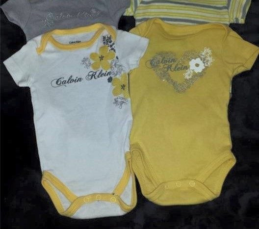 Calvin Klein brand onesies one yellow with white flower and one white with yellow and silver flowers