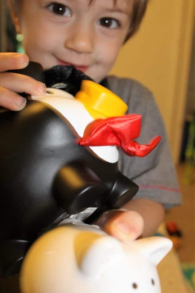 blonde male child holding a black and white piggy bank