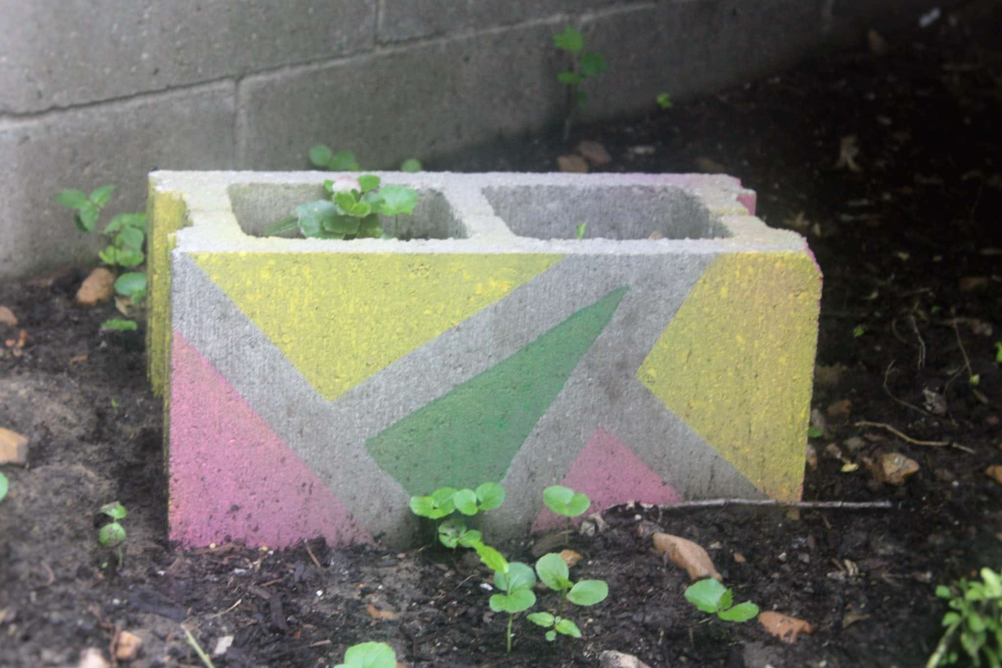 grey cinder block spray painted with green and yellow triangles