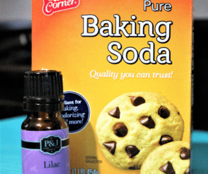 box of baking soda with a bottle of lilac essential oil in front of it