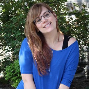 brown hair girl with glasses smiling wearing a blue shirt